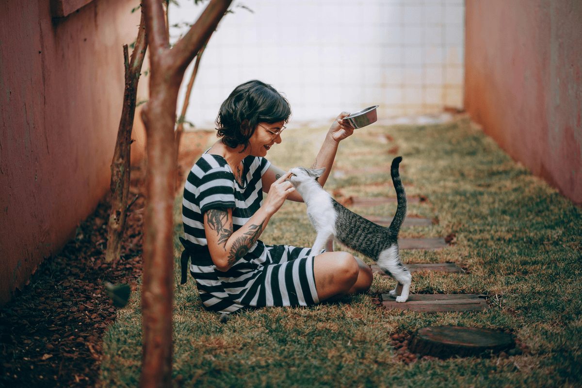 woman feeding cat outside